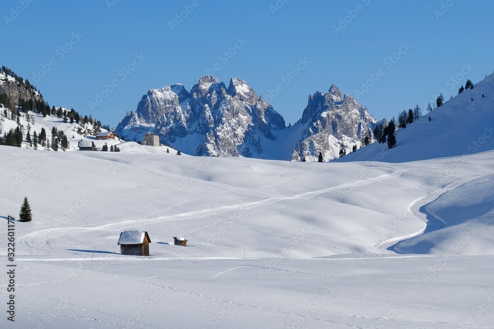 Winter mountain landscape with cross-country ski tracks and old snowy barns. Piazza Prato plateau, Sexten Dolomites, South Tyrol, Italy