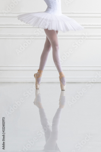 Young ballerina legs on pointe in light ballroom (Focus is on the skirt)