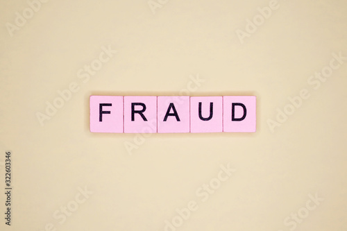 Fraud word wooden cubes on yellow background.