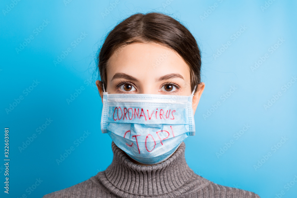 Portrait of a woman in medical mask with stop coronavirus text at blue background. Coronavirus concept. Respiratory protection - obrazy, fototapety, plakaty 
