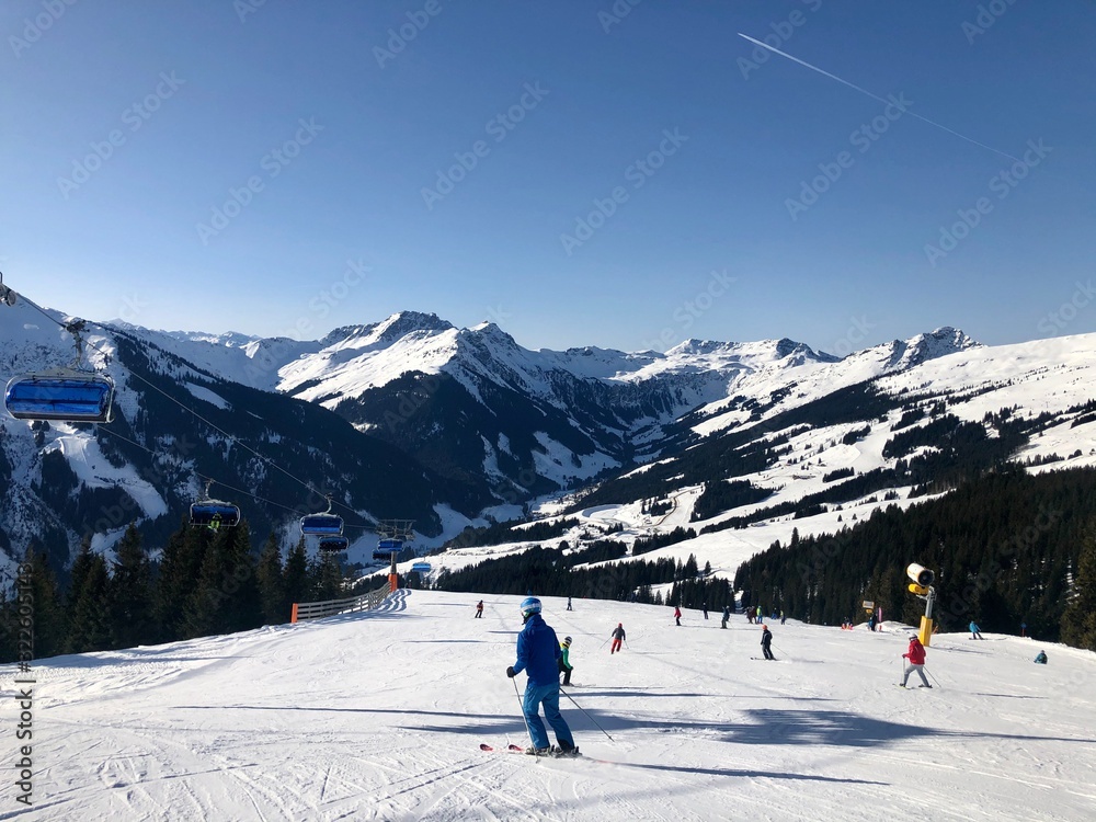 Beautiful ski panorama: Ski slope with ski lifts (chairlifts) and unidentifiable skiers in front of mountain panorama in Saalbach-Hinterglemm, Austria.