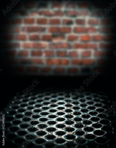 metal perforated table surface in a dark basement against a brick wall close up