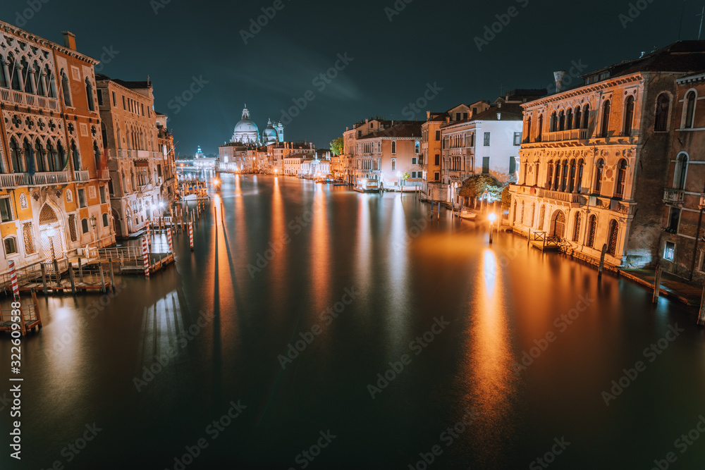 Venice, Italy. Night scene at Grand Canal with reflected light at water surface. Majestic Basilica di Santa Maria della Salute in background