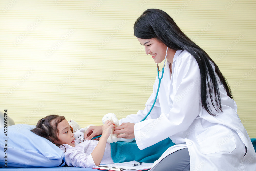 Fototapeta premium Asian female doctors use stethoscope to check the heartbeat A little girl in a hospital bed. Concept of child care.