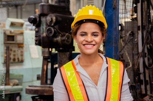 Portrait of a smile female mechanical engineer or employee worker with yellow safety helmet in a factory.
