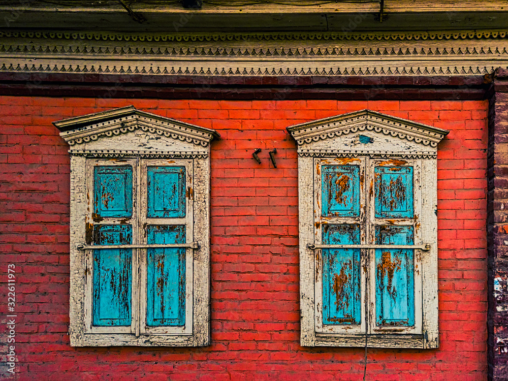 Closed wooden shutters on the windows in the red brick wall of the house Closed wooden shutters on the windows in the red brick wall of the house