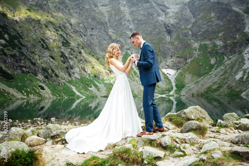 The bride and groom near the lake in the mountains. A couple together against the backdrop of a mountain landscape. Morskie Oko Lake. Tatra mountains in Poland.