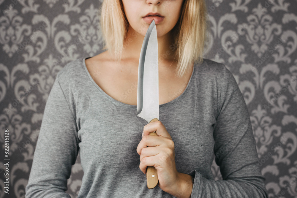 woman blonde holding a kitchen knife in her hand, threat, murder, domestic violence - obrazy, fototapety, plakaty 