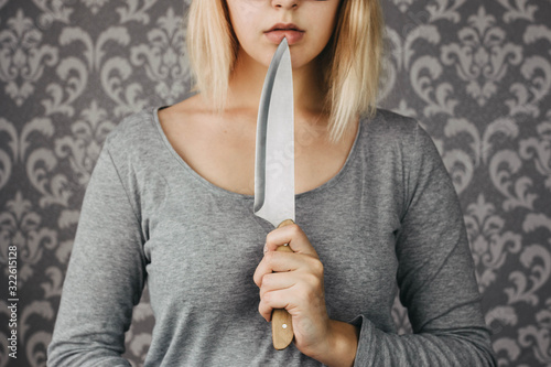 Картината върху платно woman blonde holding a kitchen knife in her hand, threat, murder, domestic viole