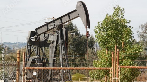 Industrial urban landscape. La Brea Inglewood in Los Angeles. Well pump jack operating behind the fence. Drilling rig extract crude oil. Oil mining machine with working piston. Oil and gas industry.