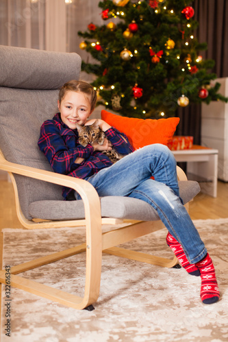 Little girl playing with cute kitty near christmas tree © oksix
