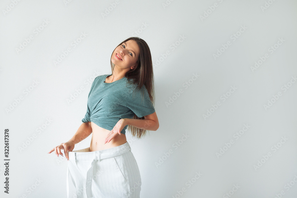 Dieting and fitness. Impressive result. Girl shows big size of her pants  and slim belly. Slim fit woman denim pants. Girl on diet lost weight white  background. Loss weight concept. Healthy lifestyle