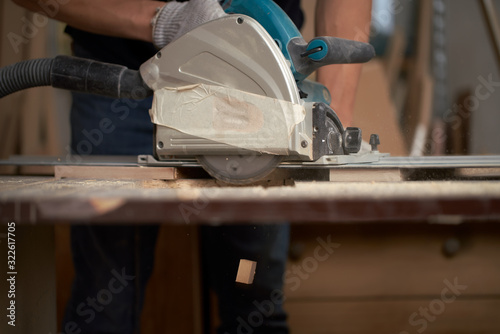 Carpenter man sawing wooden boards with jigsaw