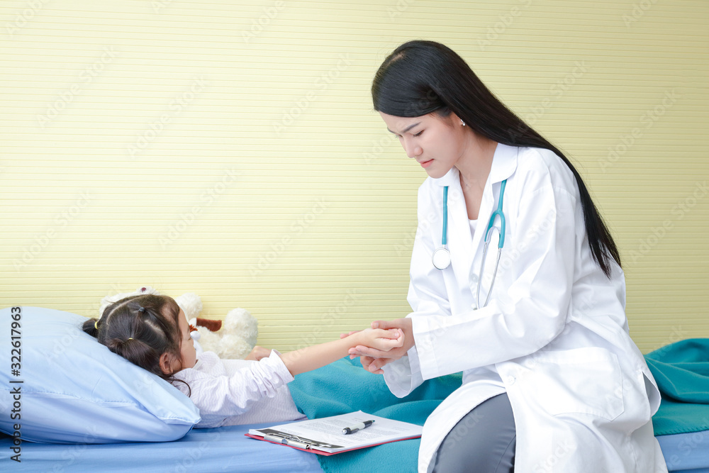Obraz premium The doctor used a hand to hold the pulse on the right wrist of a little girl in a hospital bed. Child Care concepts