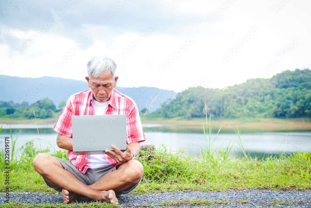 Elderly men Asians sit and type in notebooks to work outdoors in the natural park. The concept of a retirement community