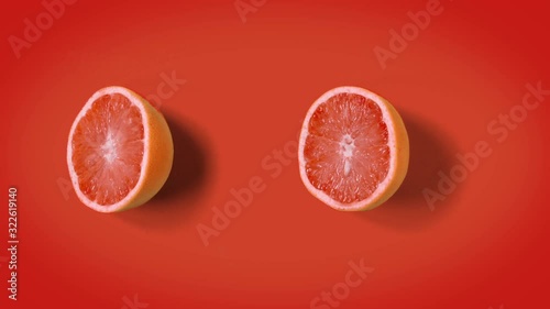 Stop motion minimal animation Top view on grapefruit halves rotating, wiggling or dancing on orange background. loopable. Real fruits. 4k.
