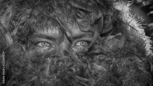 A woman's face hidden behind a feather boa.