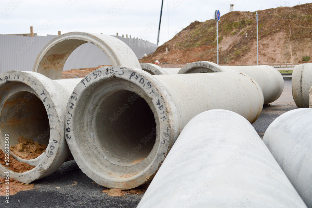 Large concrete stone cement sewer plumbing pipes of large diameter for the industrial construction of water supply or sewage at a construction site during the repair Large concrete stone cement sewer plumbing pipes of large diameter for the industrial construction of water supply or sewage at a construction site during the repair