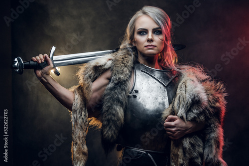 Obraz na plátně Portrait of a beautiful warrior woman holding a sword wearing steel cuirass and fur