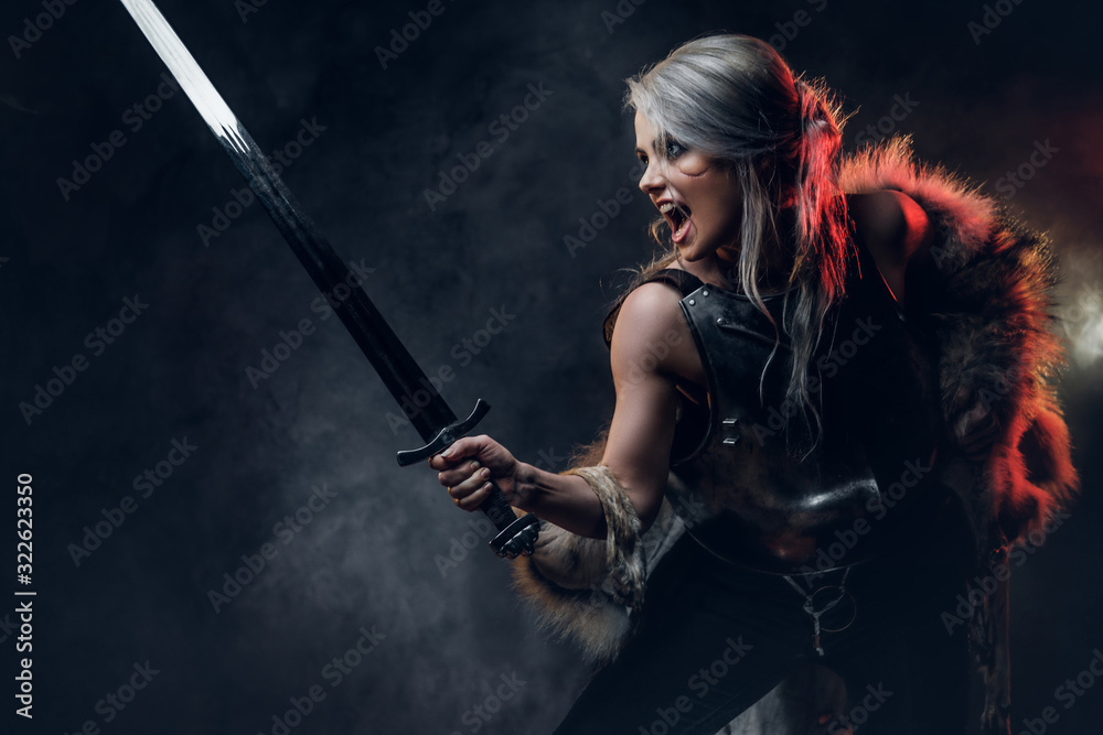 Portrait of a beautiful warrior woman holding a sword wearing steel cuirass and fur. Fantasy fashion. Studio photography on a dark background. Cosplayer as Ciri from The Witcher. Portrait of a beautiful warrior woman holding a sword wearing steel cuirass and fur. Fantasy fashion. Studio photography on a dark background. Cosplayer as Ciri from The Witcher.