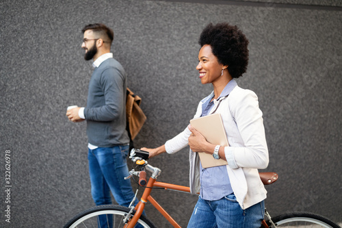 Happy cheerful businesswoman going to work by bicycle photo