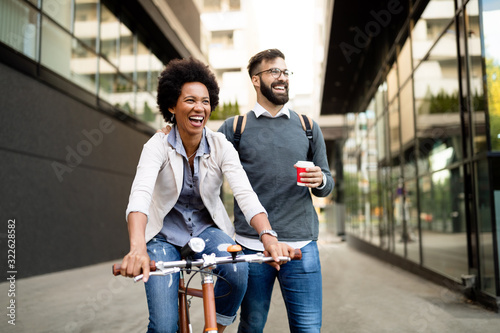 Happy business couple riding bike through city and having fun