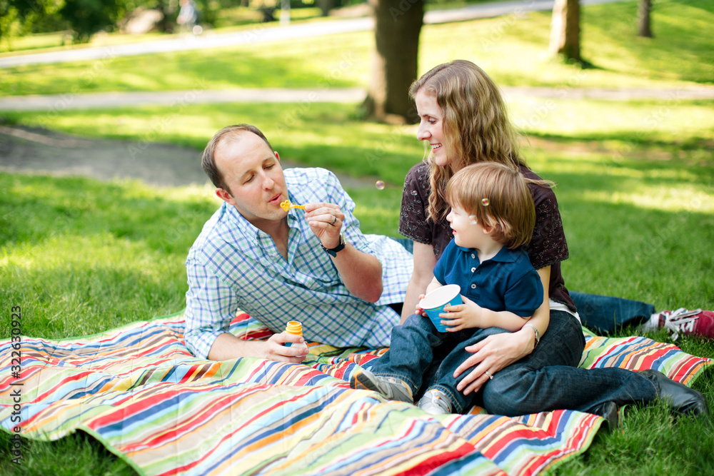 Family blowing bubbles with son in the park Family blowing bubbles with son in the park