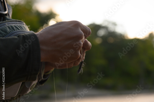 A man tying on an artificial fly called a wooly bugger