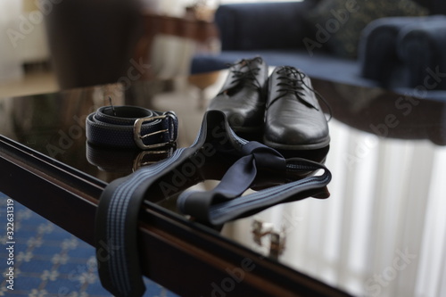 men's shoes, belt and tie on the table