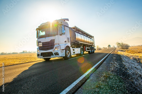 Close up of a fuel delivery truck driving by on an deserted ountry road on a beautiful sunny morning. photo