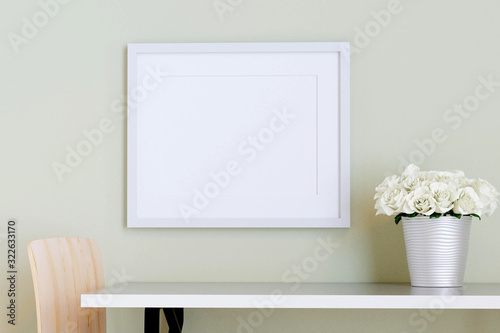 White picture frame on the wall with table and flower in a vase. 3d render.