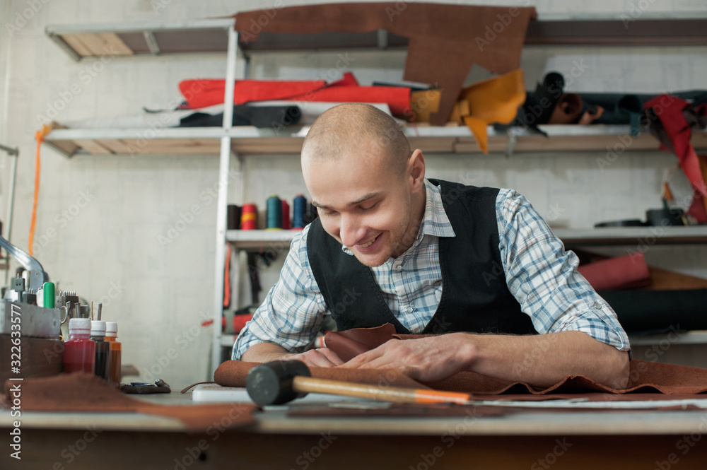 Man working with leather at a workshop. Handmade craft production of leather goods. Man working with leather at a workshop. Handmade craft production of leather goods.