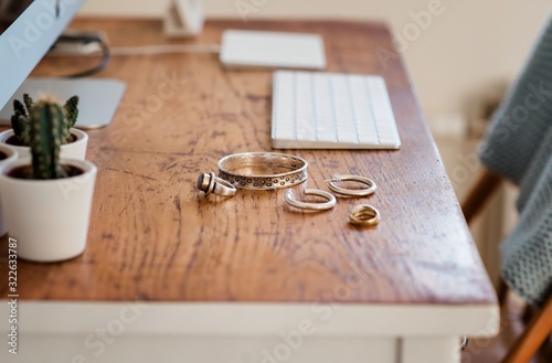 Woman's silver jewellery on a desk next to a computer photo
