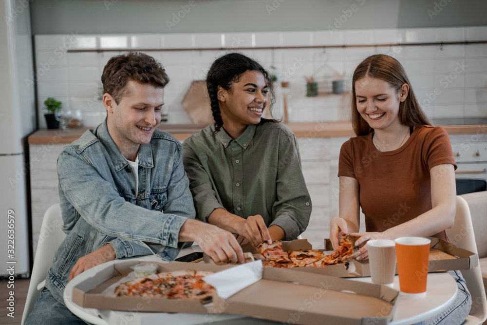 Friends eating pizza together, junk food, celebrating holiday, lunch time or evening activity. International friendship, happy time together, friends having relax time. Enjoy communication and holiday