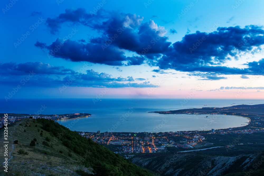 Gelendzhik Bay from a bird's eye view.  photo at sunset. Caucasus mountains in the foreground. illuminated streets of the city. dark blue sky, beautiful dark clouds