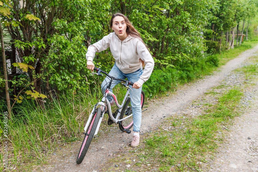 Naklejka premium Young woman riding bicycle in summer city park outdoors. Active people. Hipster girl relax and rider bike. Cycling to work at summer day. Bicycle and ecology lifestyle concept