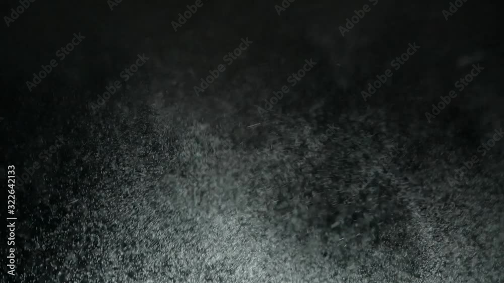Abstract shot of flying snow and steam on black background. Snow and steam flying out of a cannon are in the dark. Snowy weather causes strange feelings of winter days and a feeling of something cool.