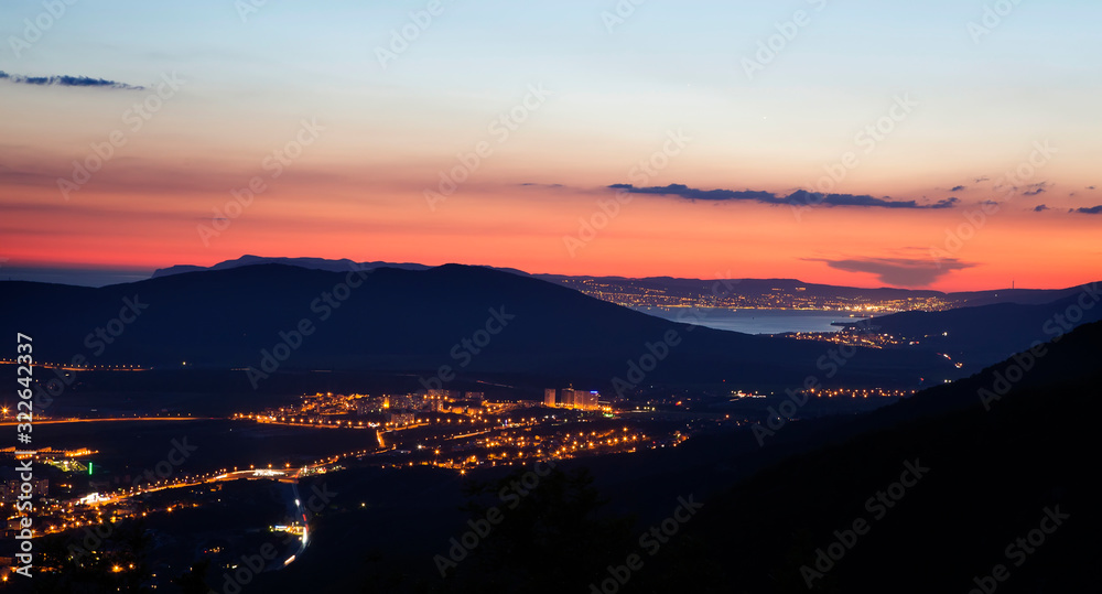 panorama of Novorossiysk Bay at night from the Caucasus mountains. bright lights, reflection in the water. car lights, mountains. roads. 