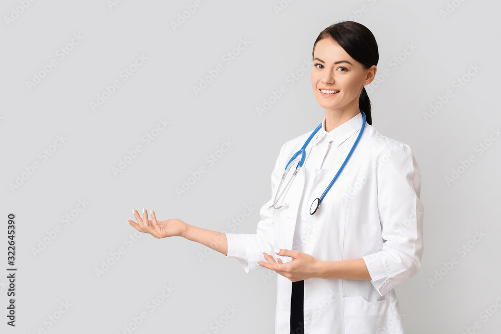 Female cardiologist showing something on light background Female cardiologist showing something on light background