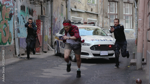 Photos Two policemen run for a criminal pistol arrest bad guy street city crime danger
