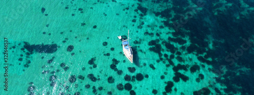 Aerial drone ultra wide photo of sail boat docked in tropical exotic bay with emerald coral reef