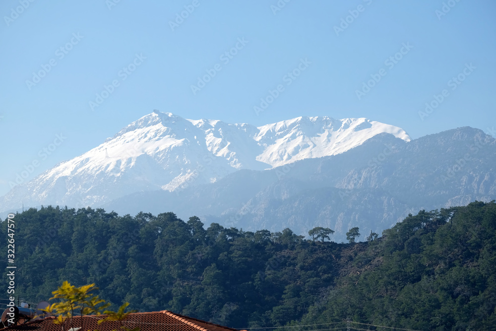 Panoramic landscape with Turkish mountains of different heights, mountain pines on the slopes and snow on high peaks at far