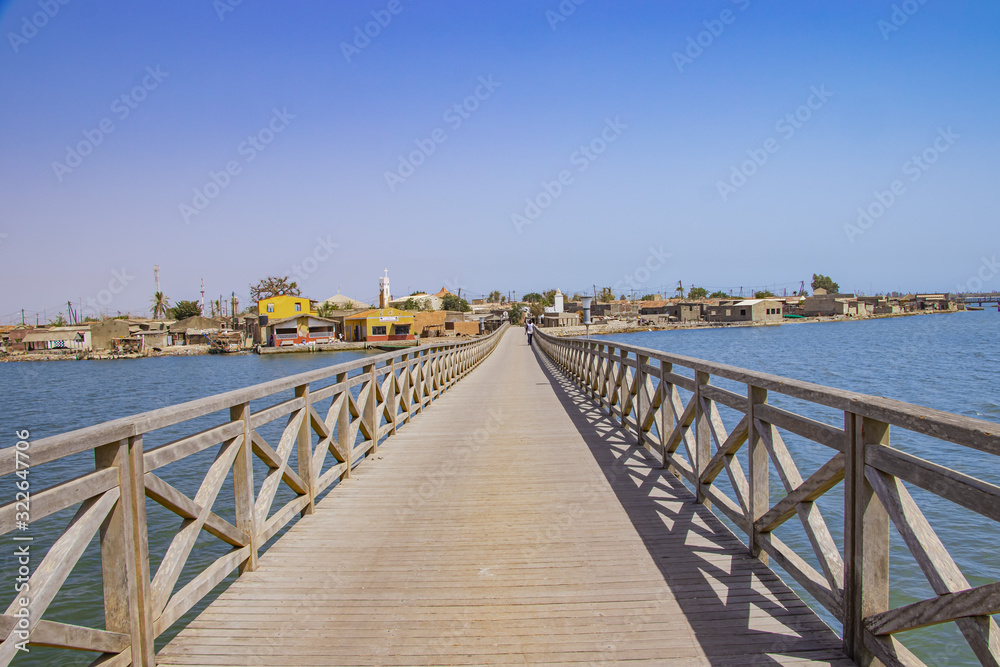 Long wooden bridge leading over a sea lagoon. It leads to Fadiouth Island in Senegal, Africa. It is a beautiful natural background.