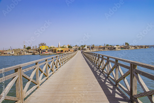 Long wooden bridge leading over a sea lagoon. It leads to Fadiouth Island in Senegal  Africa. It is a beautiful natural background.