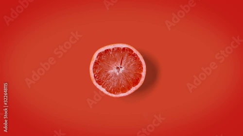 Stop motion minimal animation Top view on half grapefruit rotating, wiggling or dancing on orange background. loopable. Real fruits. 4k.
