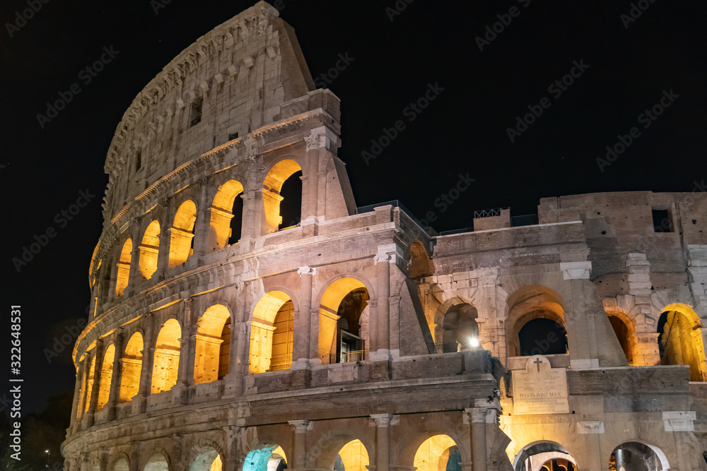 The Colosseum under the glow of lights at night, ancient roman arena, Rome