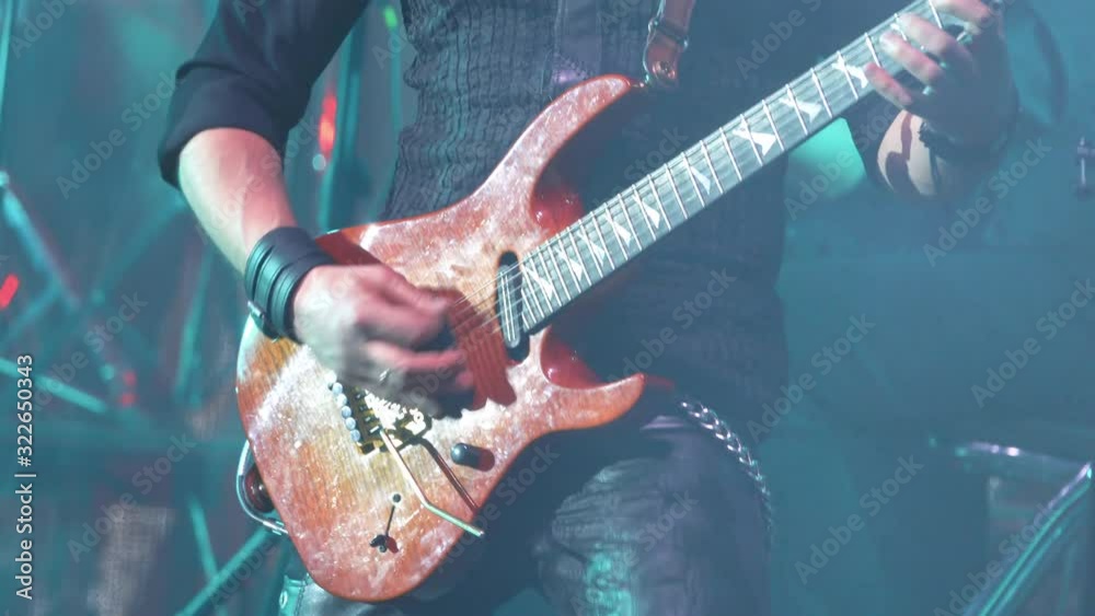 A virtuoso guitarist playing an electric guitar on stage with flashing LED lights.