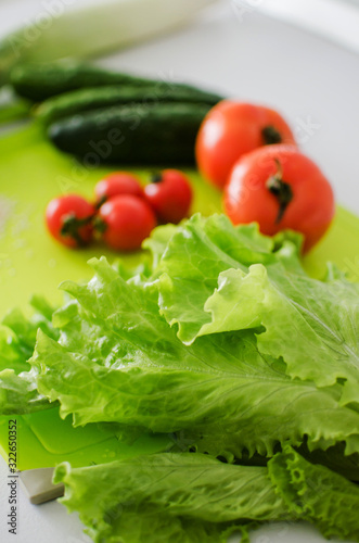 Bowl with salad and fresh vegetables on kitchen table. Healthy food