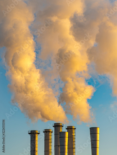 Yellow smoke go out of multiple chimneys with background of blue sky