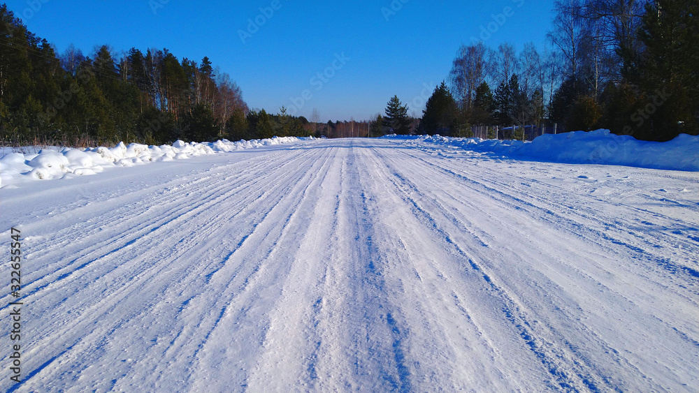 Winter road in white snow, going into the horizon against the blue sky Winter road in white snow, going into the horizon against the blue sky